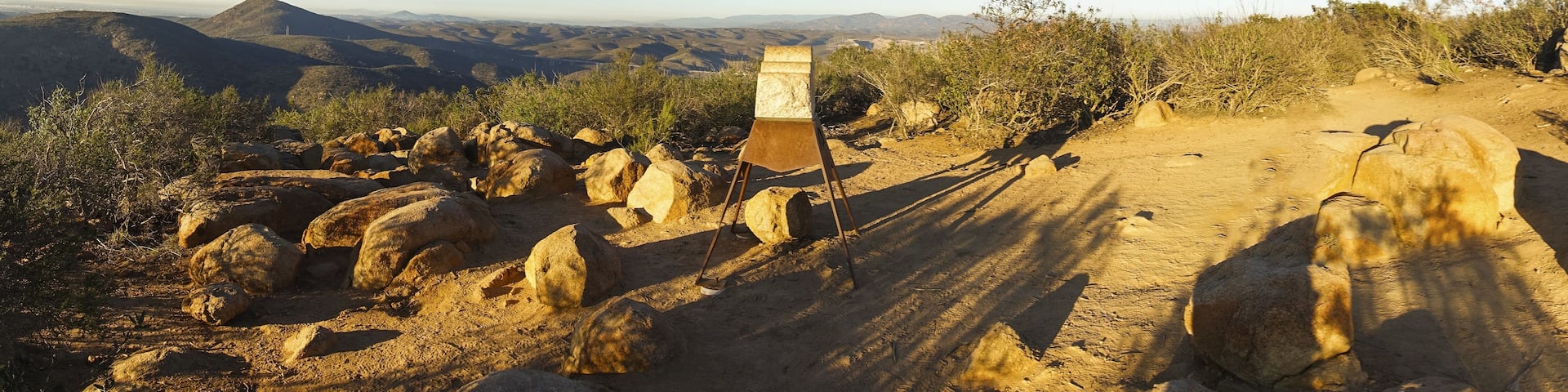 A rocky terrain with a metal signpost amidst a desert landscape.