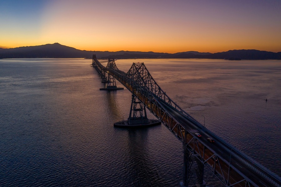 The Richmond-San Rafael Bridge spans San Pablo Bay in Richmond, California, USA, connecting counties. Cars travel across at sunset.