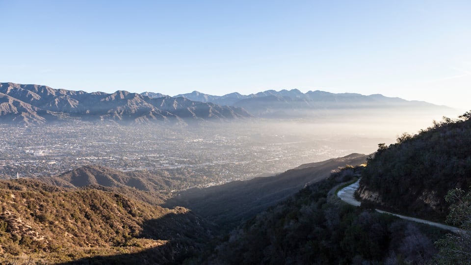 A mountainous landscape with a winding road and a valley below.