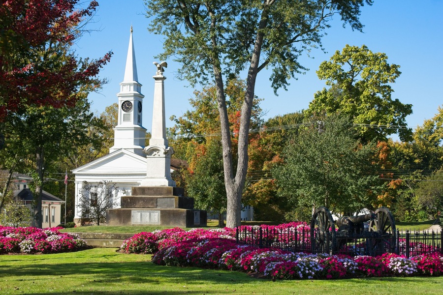 Colorful beds of flowers cluster on the town square in Twinsburg, Ohio, with in front of the civil war monument and a historic old church.