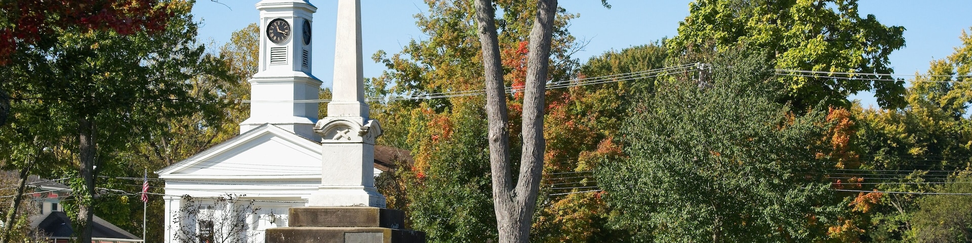 Colorful beds of flowers cluster on the town square in Twinsburg, Ohio, with in front of the civil war monument and a historic old church.