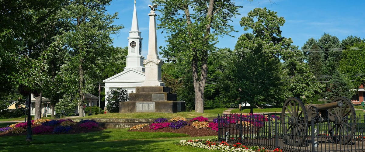 Summer on Twinsburg Square with Civil War monument and cannon in front of a historic old church