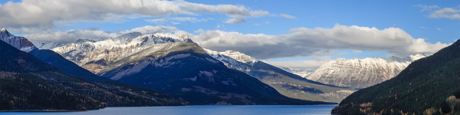 A lake surrounded by snow-capped mountains and dense forests.