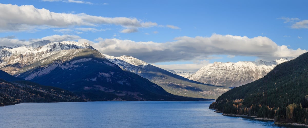 A lake surrounded by snow-capped mountains and dense forests.