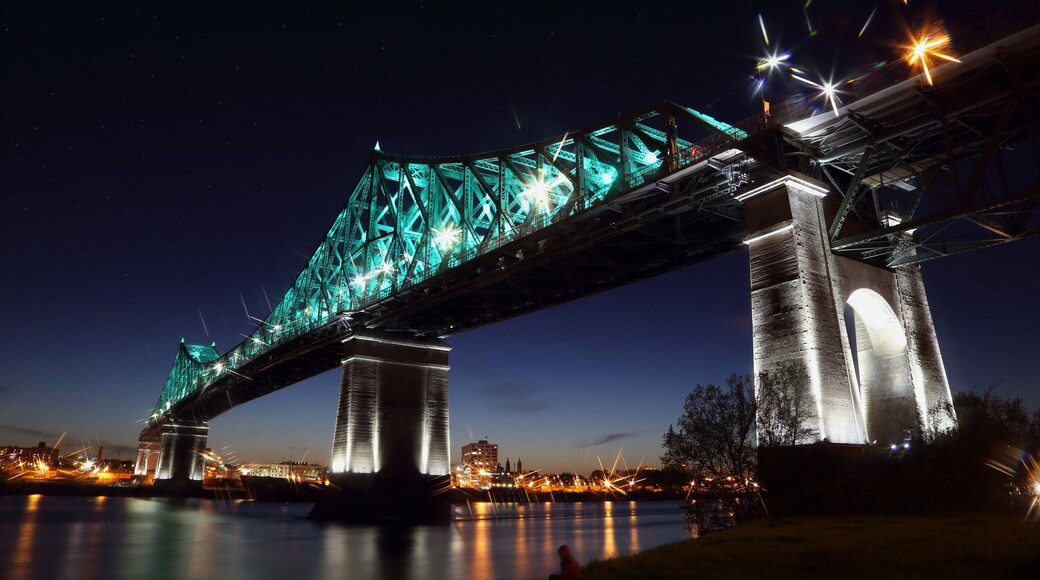 Jacques Cartier Bridge Illumination in Montreal, reflection in water. Montreal’s 375th anniversary. luminous colorful interactive Jacques Cartier Bridge. Bridge panoramic colorful silhouette by night.