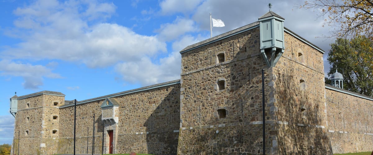 A historic stone building with a flagpole, a small tower, and a flag.