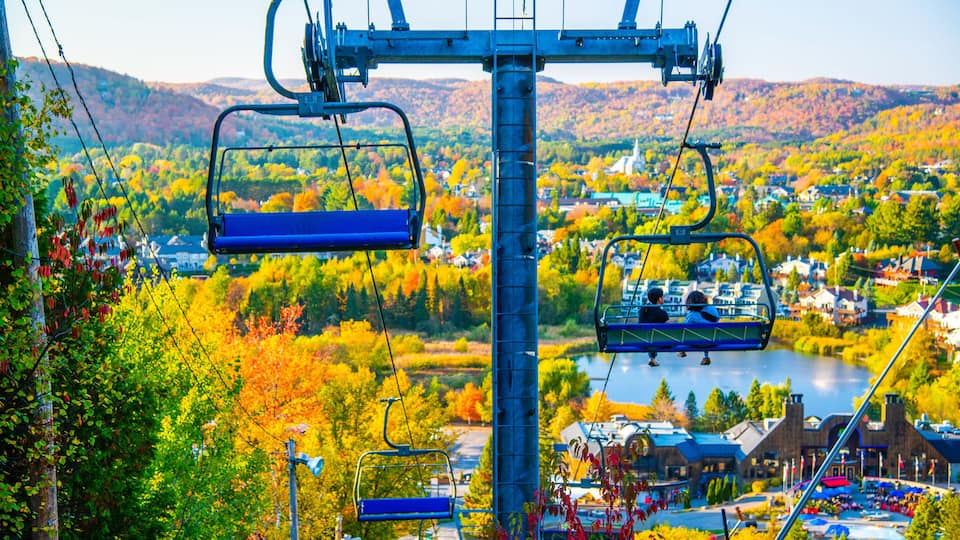 A cable car system with a view of a town and autumn foliage.
