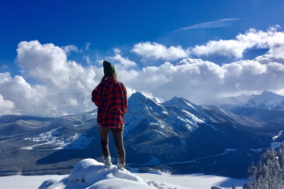 Una persona al cim cobert de neu, amb vista a una serralada.
