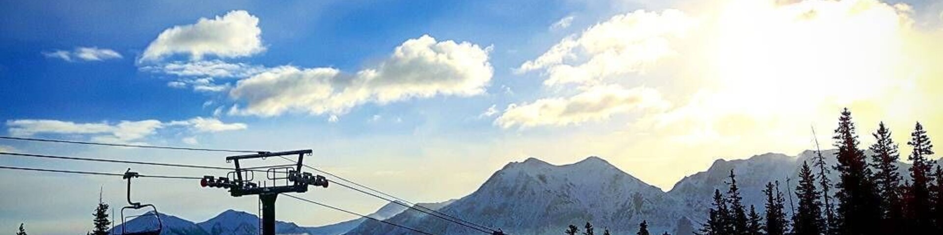 Um teleférico com paisagem nevada de montanha ao fundo.