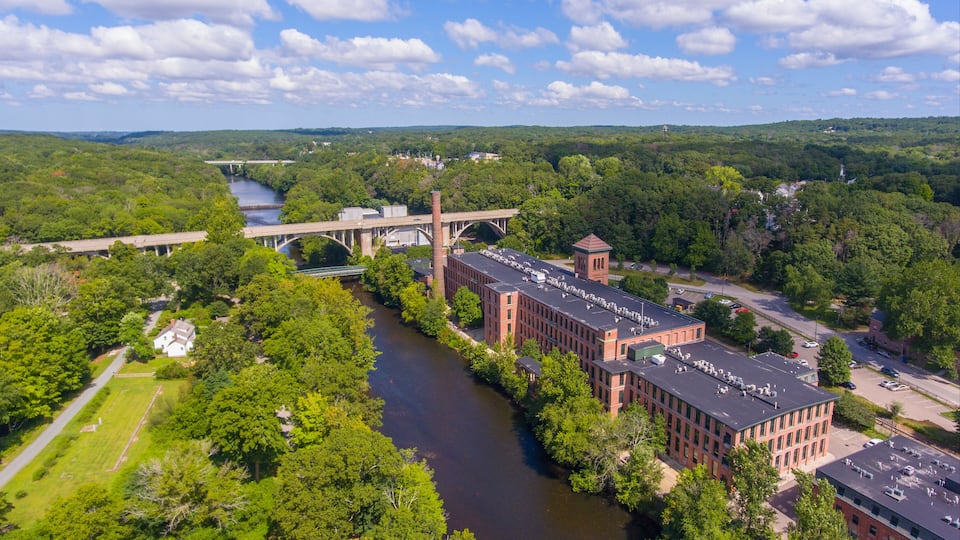 A river flowing through a campus with buildings and a bridge.