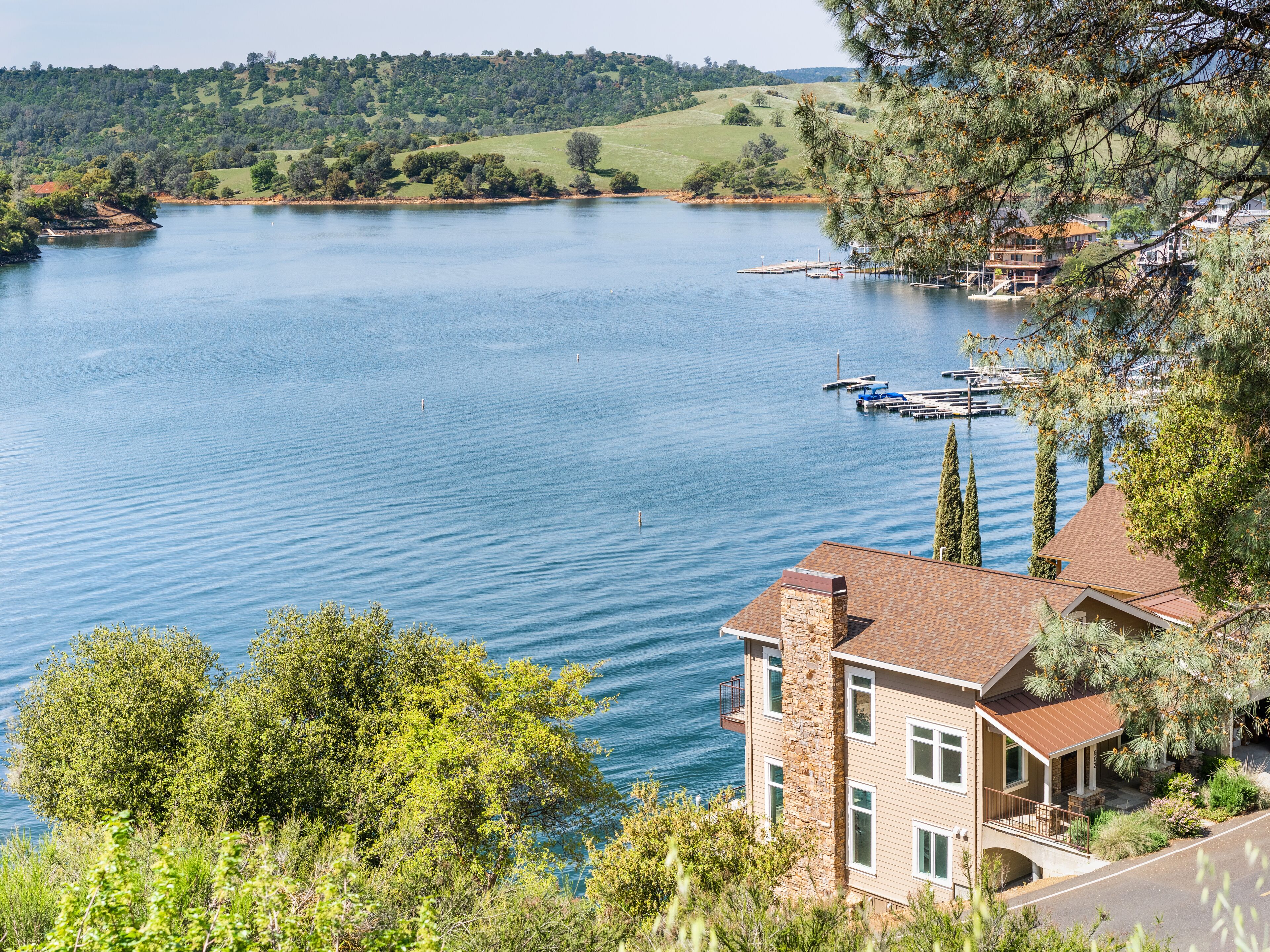 A lake with boats, a dock, and houses in the background.