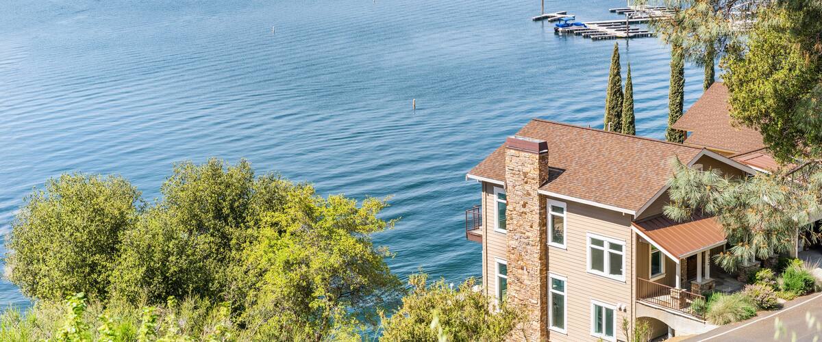 A lake with boats, a dock, and houses in the background.