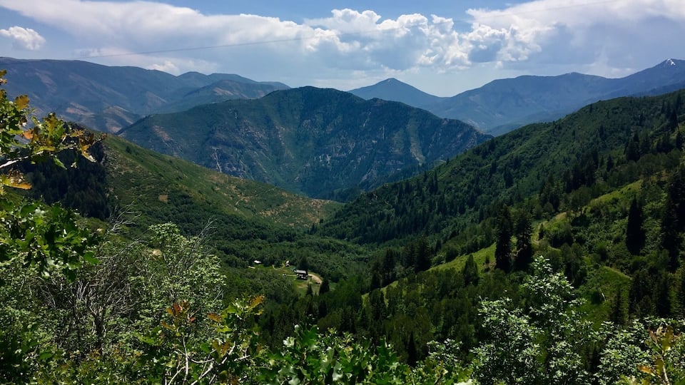 A mountainous landscape with dense forests and a clear sky.