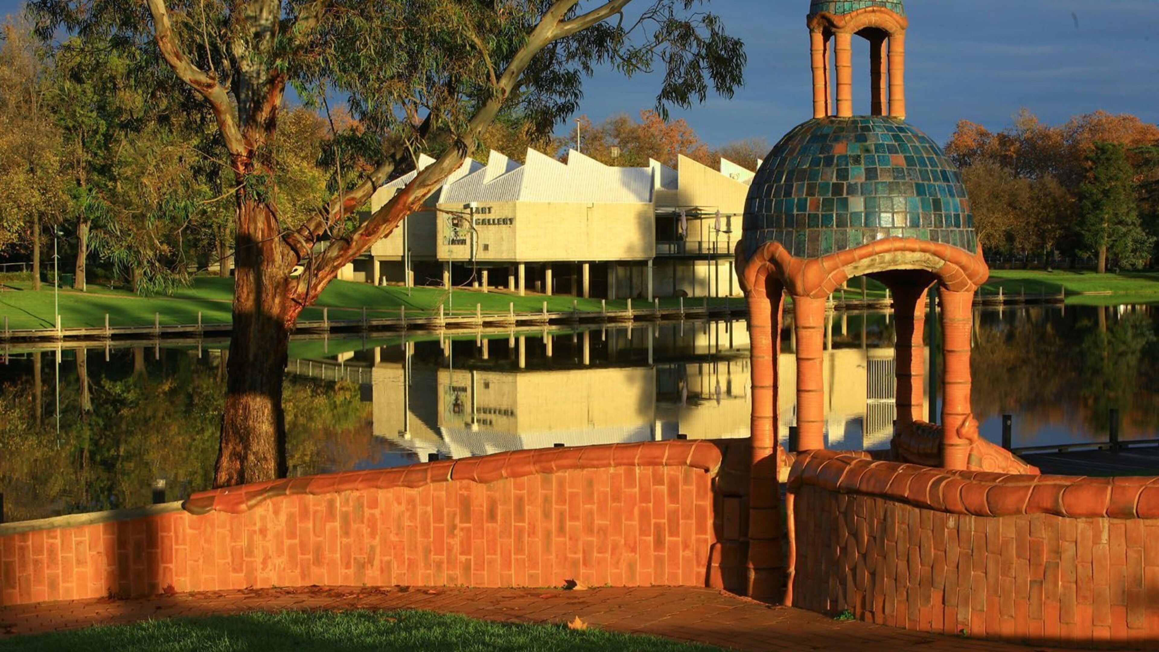A gazebo with a tiled dome and a brick wall, a pond, and a building labeled "LOT GALLERY" in the background.