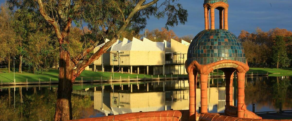 A gazebo with a tiled dome and a brick wall, a pond, and a building labeled "LOT GALLERY" in the background.