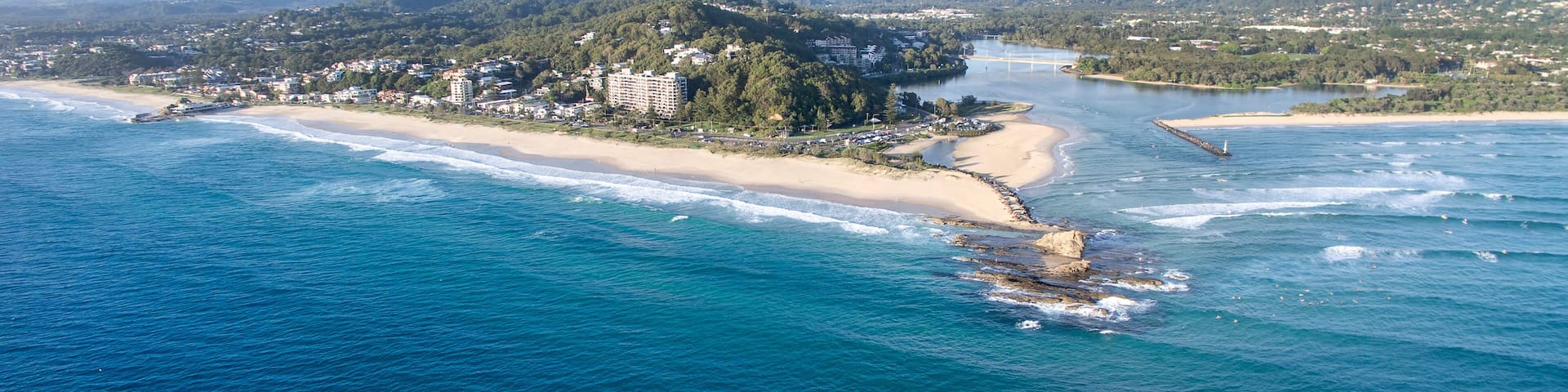A coastal town with a beach, a river, and surrounding hills.