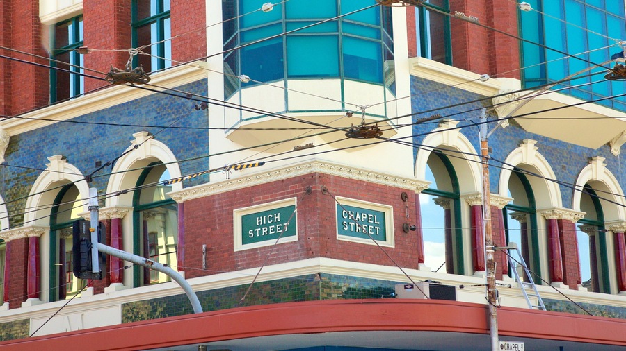 A building with 'High Street' and 'Chapel Street' signs, a red brick facade, and a blue-tiled window.