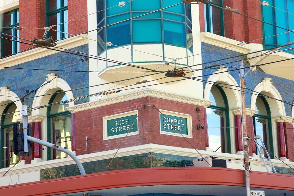 A building with 'High Street' and 'Chapel Street' signs, a red brick facade, and a blue-tiled window.