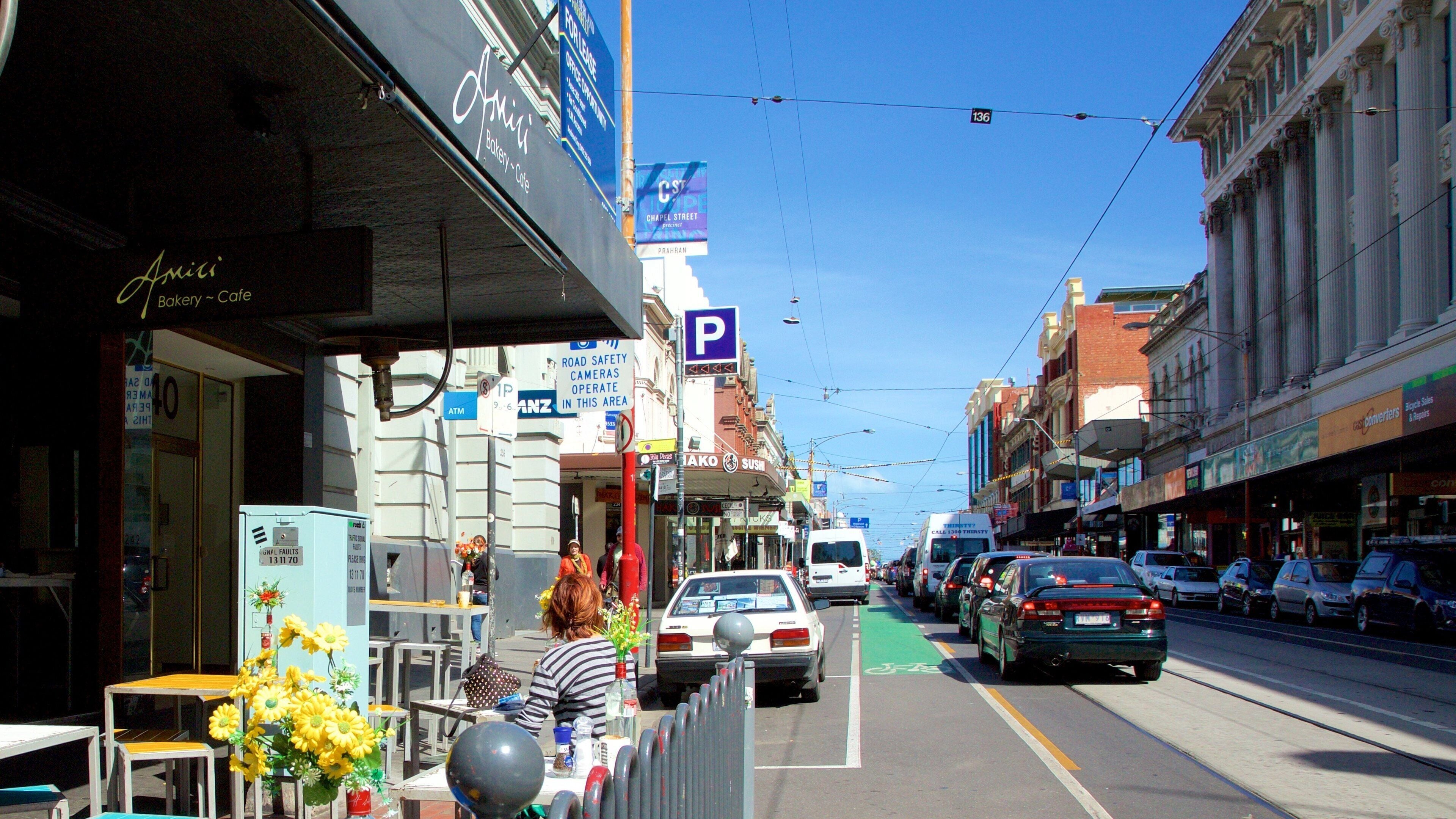 Une rue bordée de boutiques, d’une boulangerie et d’un restaurant de sushis.
