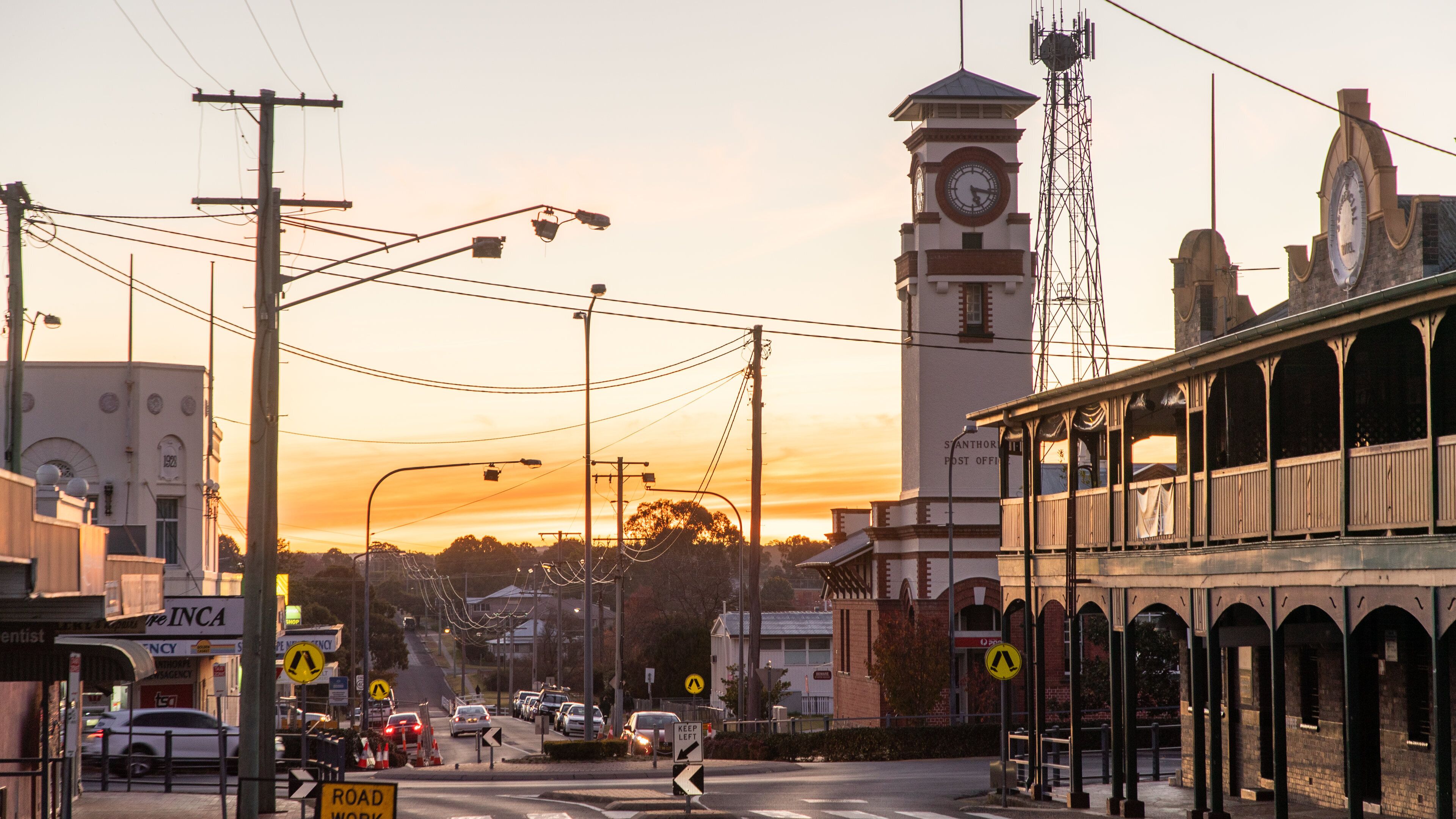 A street with a clock tower, a tram, and a building with a sign that reads "INCA".