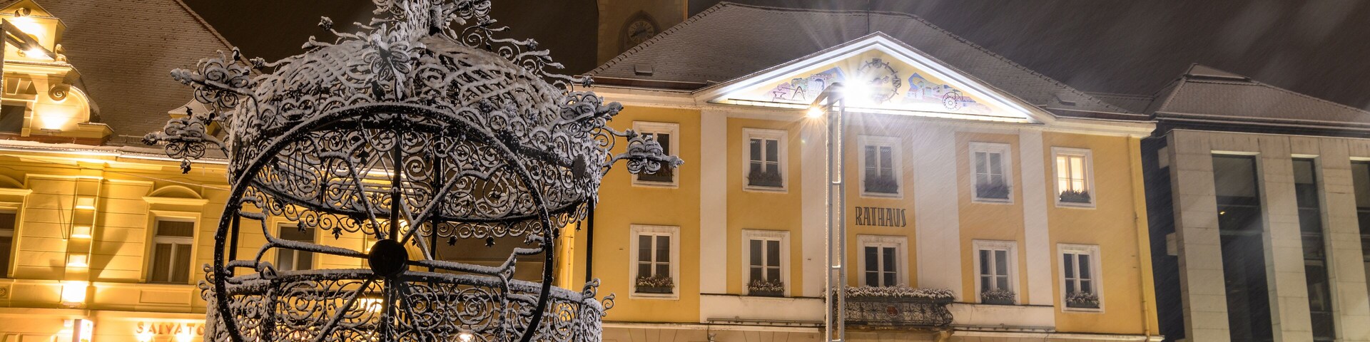 Una escultura cubierta de nieve en una plaza, con un edificio al fondo.
