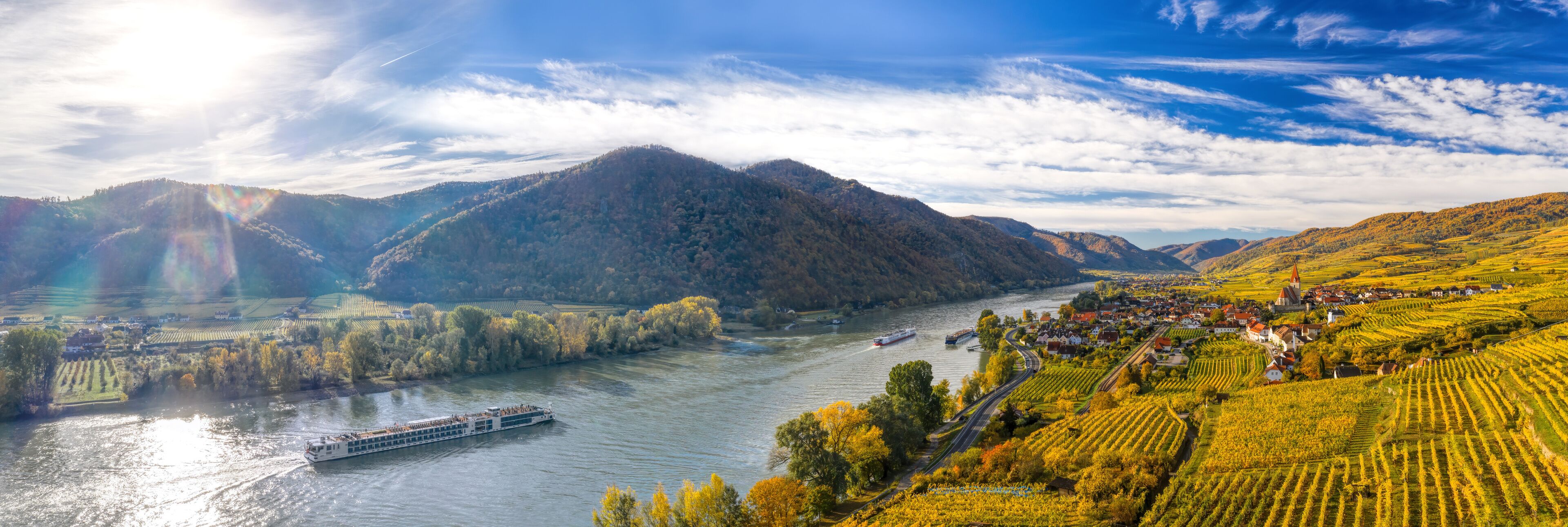 A river with boats, vineyards, and a town with houses and a church.