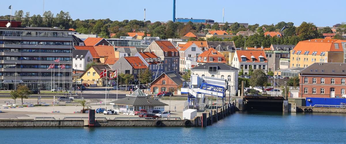 A harbor with boats, a bridge, and buildings with red roofs.