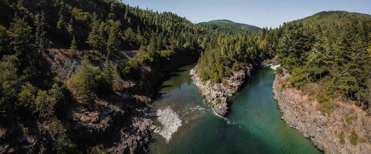 A river winding through a forested valley with rocky outcrops and dense trees.