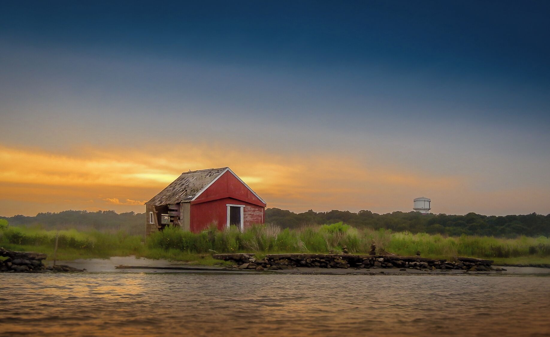 After a long day at the beach, I was paddling in my kayak back to my put in point when I came across this beautiful scene. The sun is going down over this long ago abandoned building. 

Not sure what it was. There is a old pier in the front. Maybe for fishermen? 