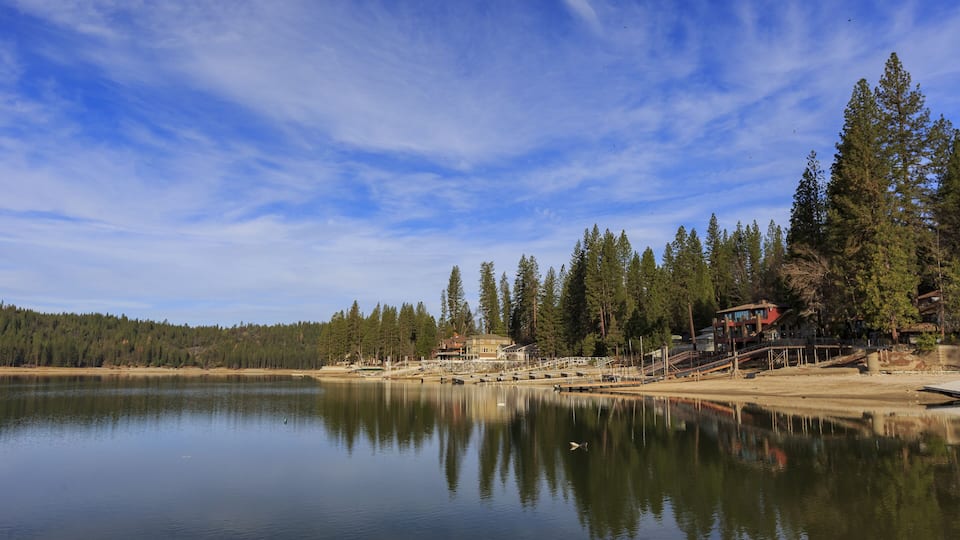 A calm lake with a wooden dock and a house on the right.