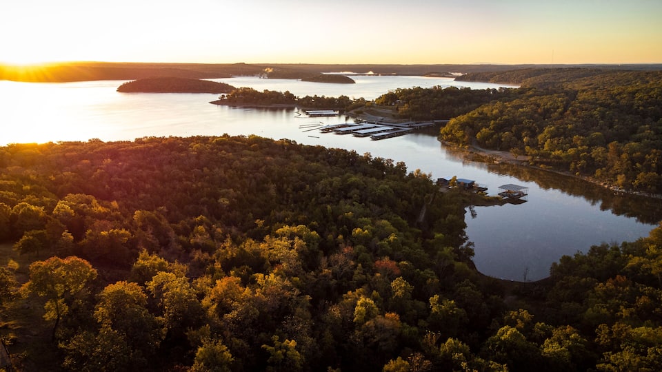 A river winding through a densely forested landscape with a small dock and buildings along the shore.