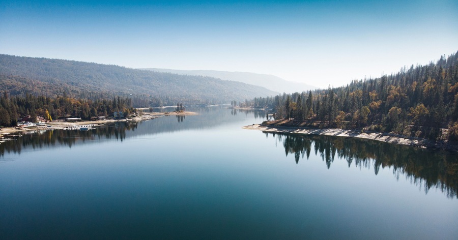 A calm lake surrounded by dense forests and hills.