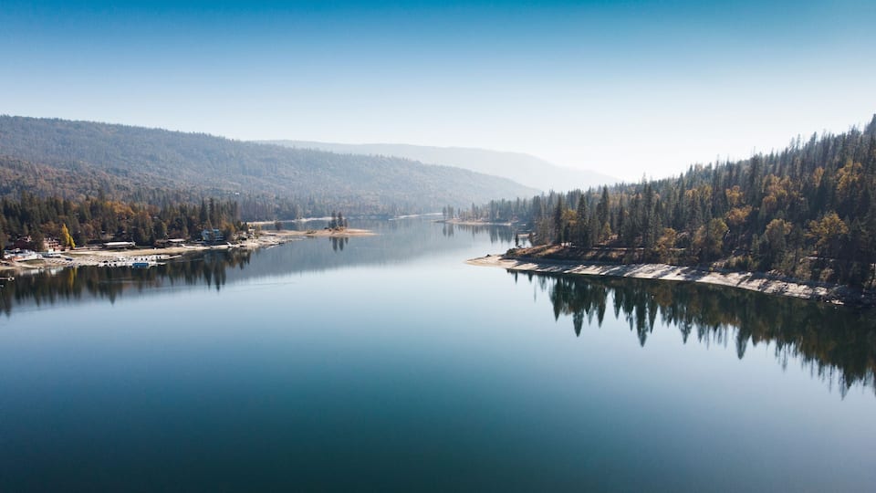 A calm lake surrounded by dense forests and hills.