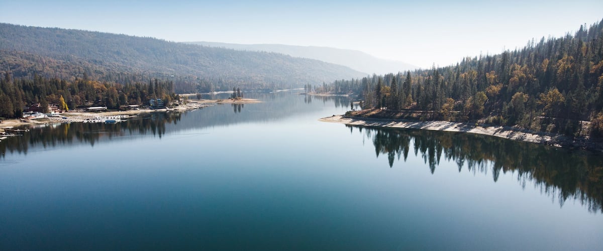 A calm lake surrounded by dense forests and hills.