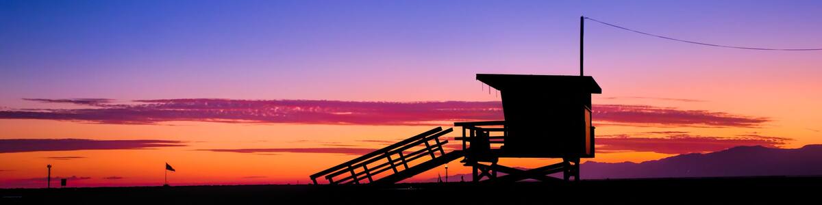 Sunset behind a lifeguard tower on the beach in Los Angeles, CA.