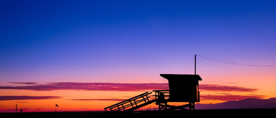 Sunset behind a lifeguard tower on the beach in Los Angeles, CA.