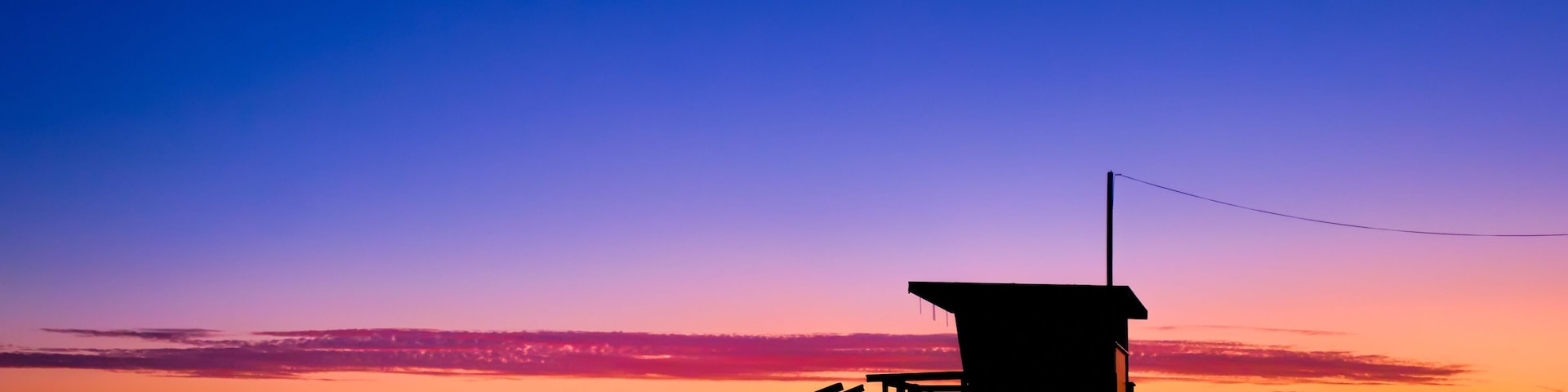 Sunset behind a lifeguard tower on the beach in Los Angeles, CA.