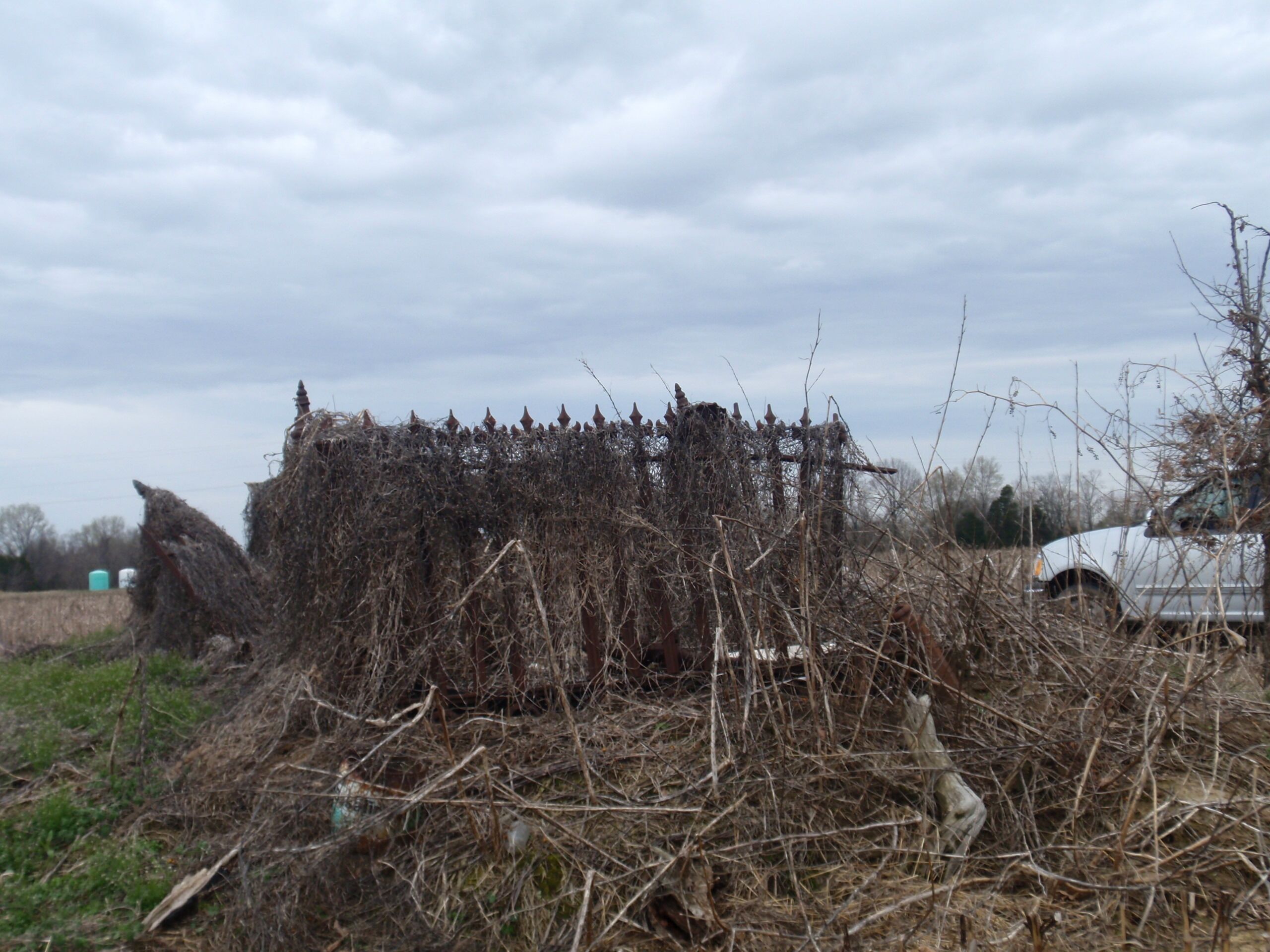 A field with hay bales and a white vehicle.