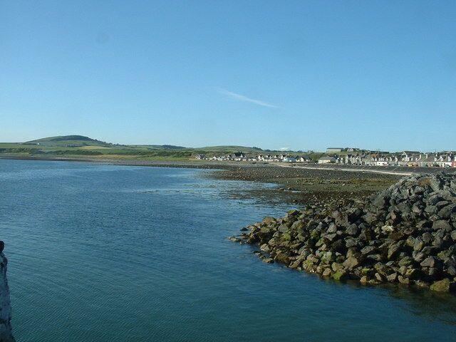 Harbour entrance, Port William. Looking north, up the coast. The linear extension of Port William is clearly seen. More housing development is planned at the far end of the line of houses.