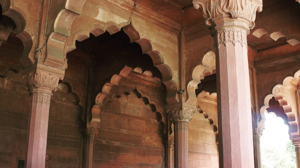 An interior with red stone arches and columns.