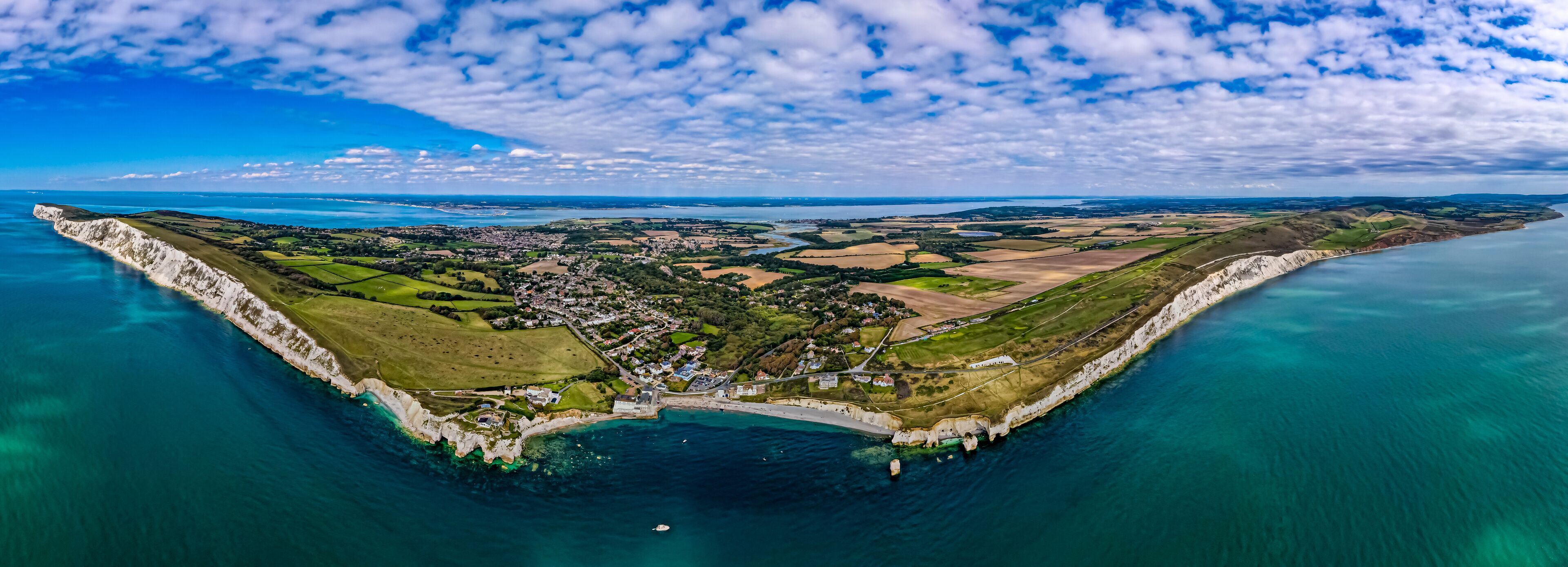 A coastal town with a prominent white cliff, a harbor, and surrounding agricultural fields.