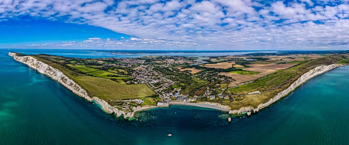 A coastal town with a prominent white cliff, a harbor, and surrounding agricultural fields.