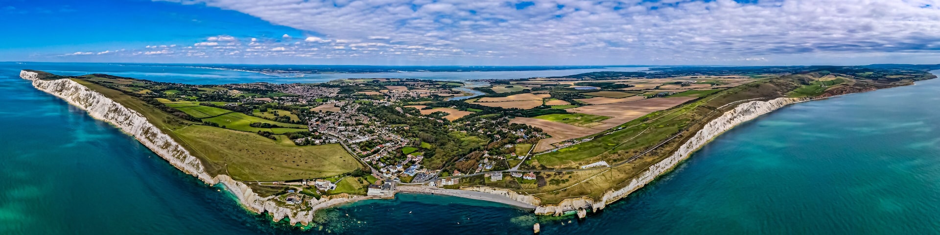 A coastal town with a prominent white cliff, a harbor, and surrounding agricultural fields.