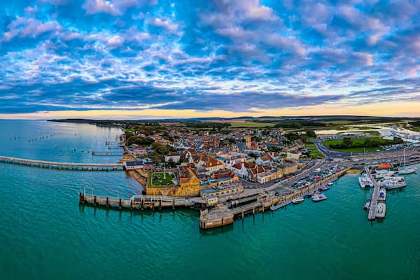 A coastal town with a pier, marina, and historic buildings.
