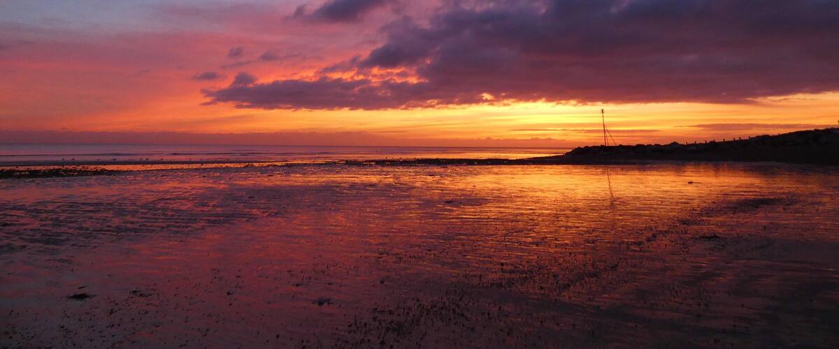 A sunset over a beach with clouds in the sky.
