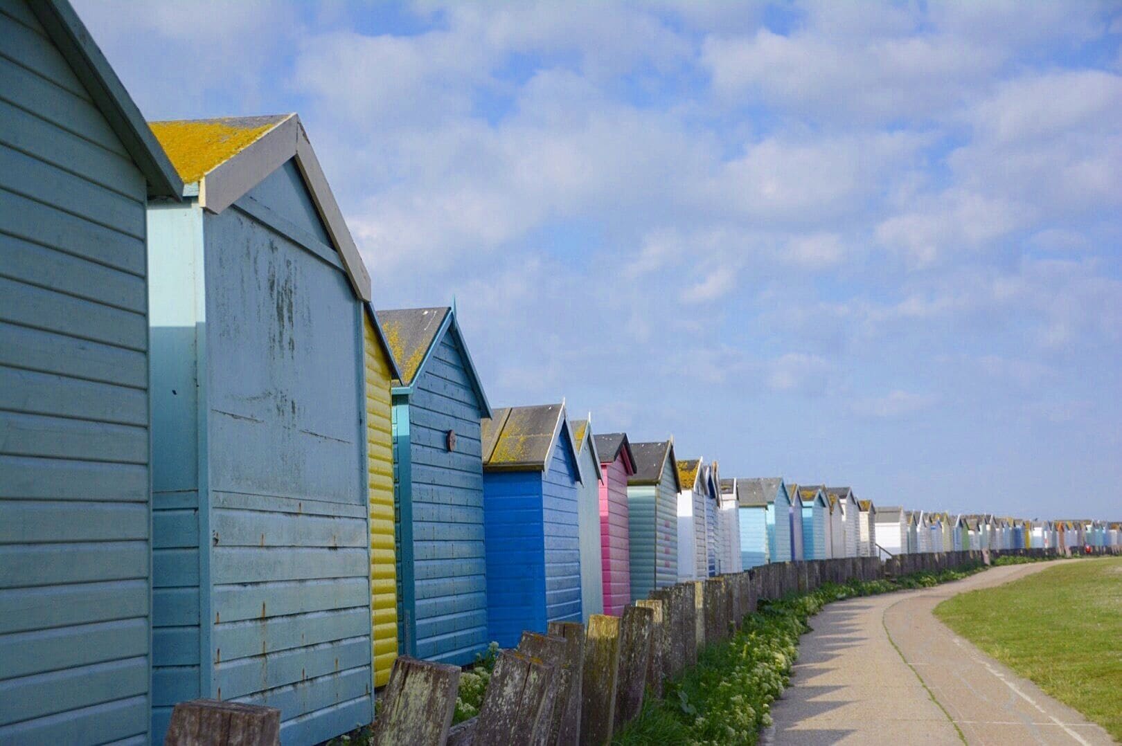 A row of colorful beach huts along a seaside path.