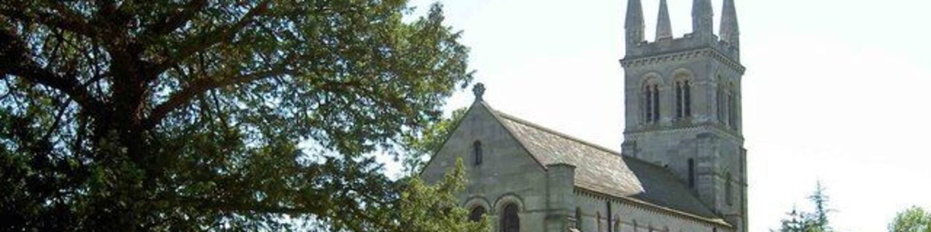 A church with a tall tower and a fenced cemetery.
