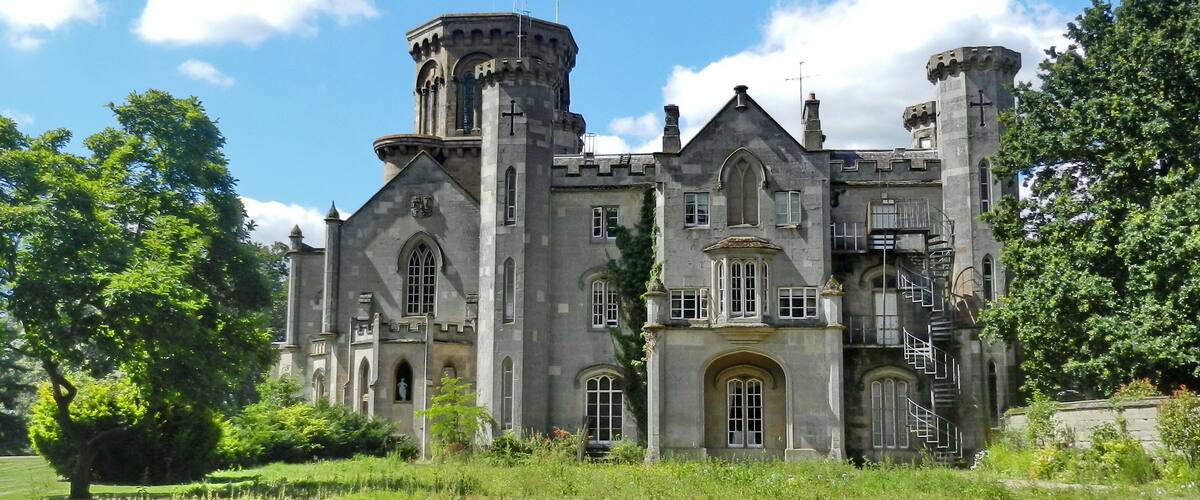 Un gran edificio de piedra histórico con múltiples torres y ventanas de arco.