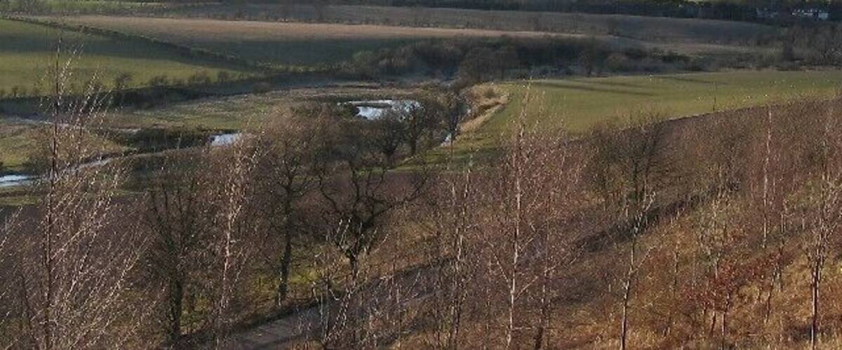 Rolling hills, a river, and a sparse tree line.
