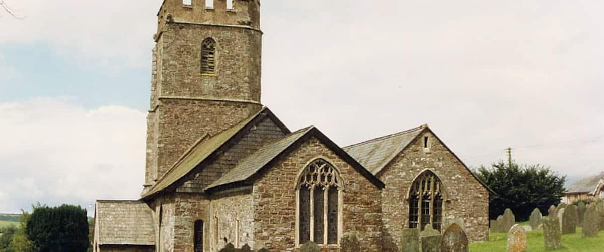 A historic church with a tall tower and arched windows, surrounded by a cemetery with headstones.